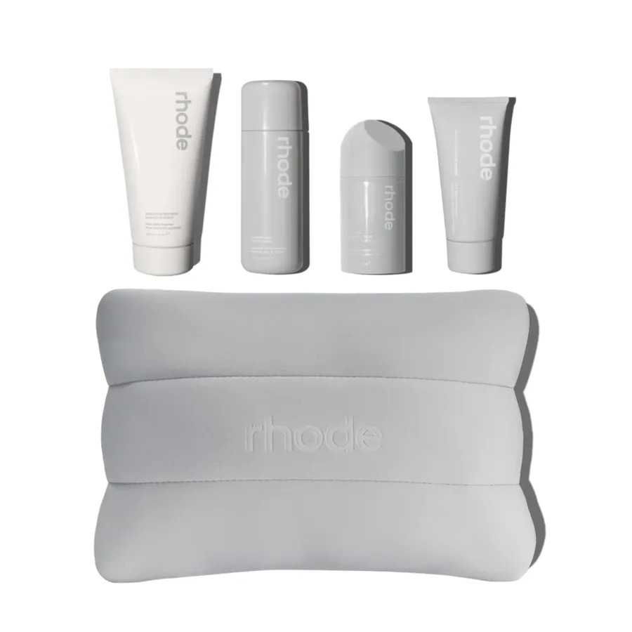 The rhode kit: four grey and cream skincare tubes with a pillow.